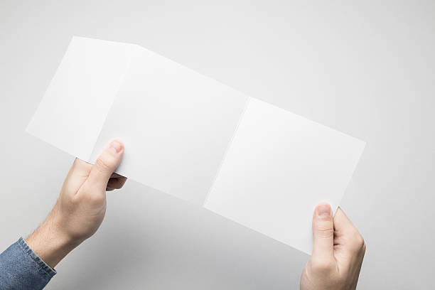 istock Hands are holding a Square Z-Fold white paper poster. 615116882