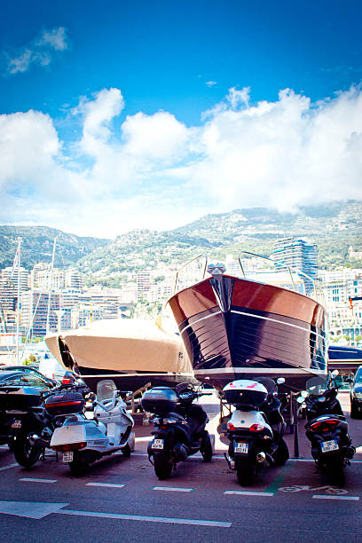 Monte Carlo, Monaco - July 30, 2015: A couple of luxury motor yachts out of the water on the harbour side in Monaco marina with a row of scooters parked in front of them.