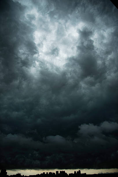 dunkle stürmische wolken über der stadt - unheilschwanger stock-fotos und bilder