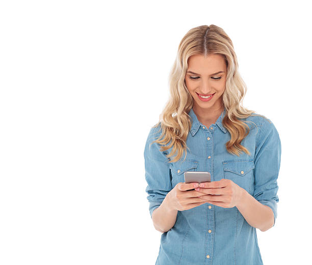 istock smiling blonde woman is reading text messages on her smartphone 615235280