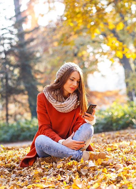 istock Young woman with smart phone relaxing in park 615236126