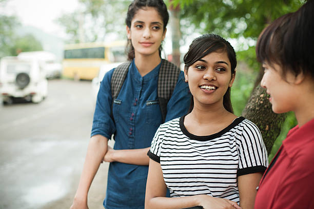 Girl students gossiping while waiting for bus by road side.