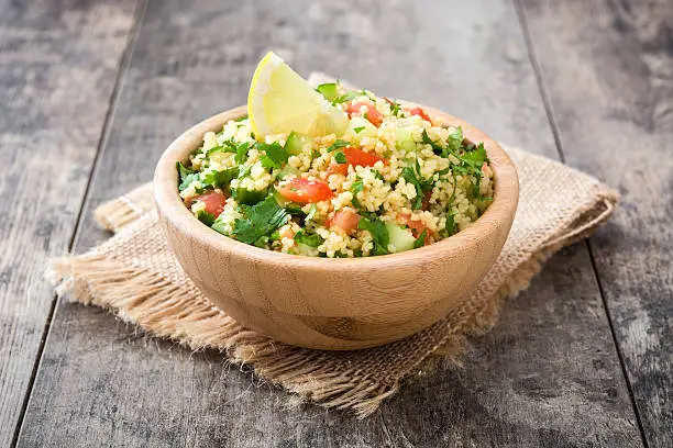 Tabbouleh salad with couscous on wooden background