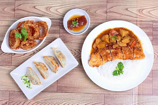 Jasmine rice with deep fried dolly fish in japanese yellow curry and side dish of steamed stuffing flour as "Gyoza is popular food for health.