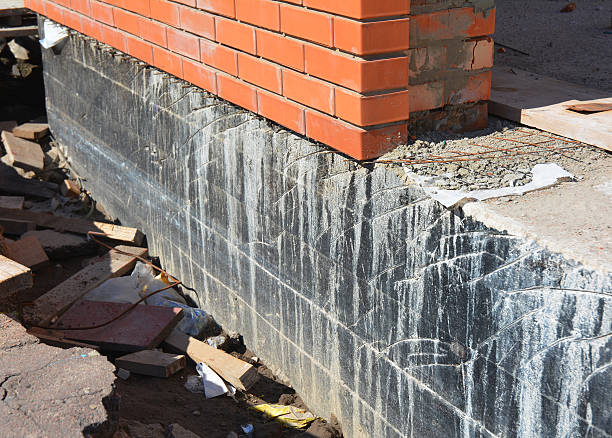 istock Waterproofing house foundation with spray on tar. 615258586