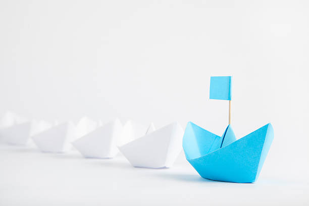 istock Leadership concept with blue paper ship leading among white 615258648