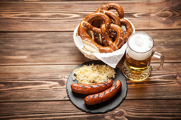 bretzels, bratwurst et choucroute sur table en bois - pretzel german culture food salt photos et images de collection