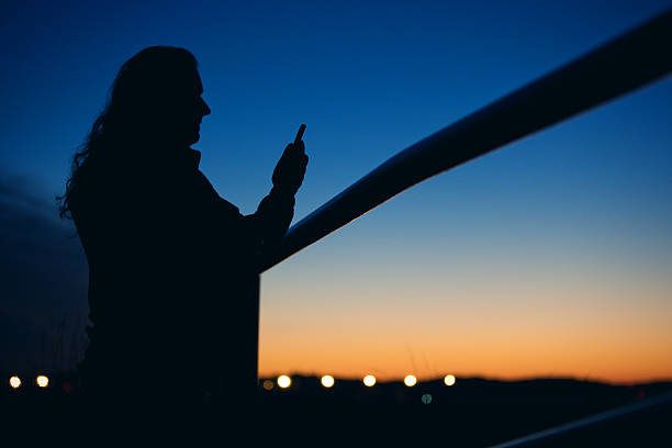 istock Silhouette Of Man Looking At His Phone During Sunset 615263400