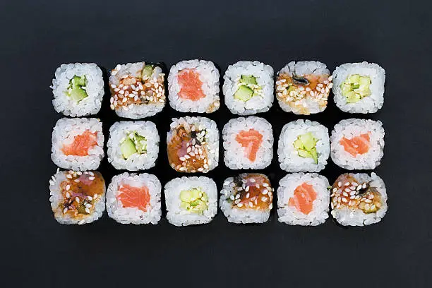 Mix of Japanese nori rolls in on a black background