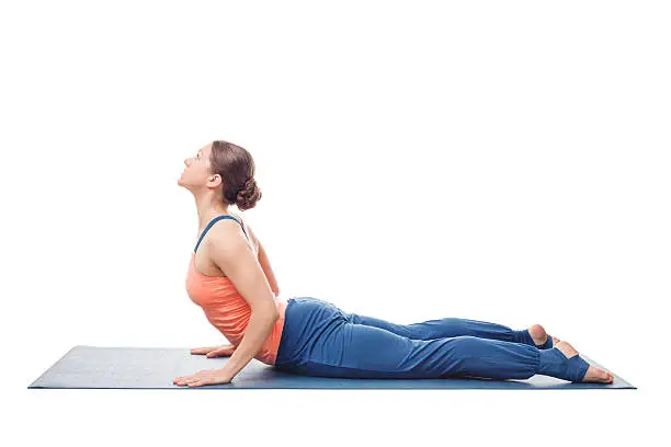 Beautiful sporty fit yogini woman practices yoga asana bhujangasana - cobra pose in studio isolated on white