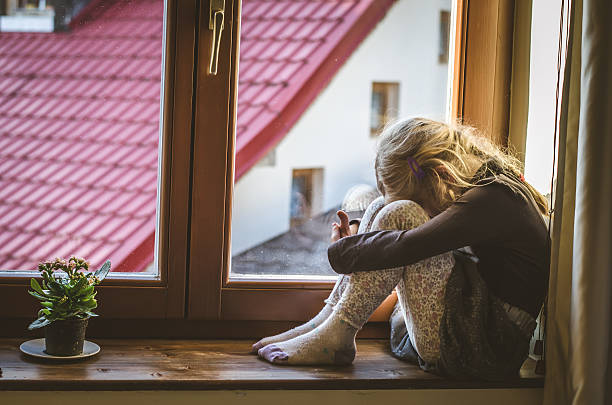 istock sad child at the window 615268842