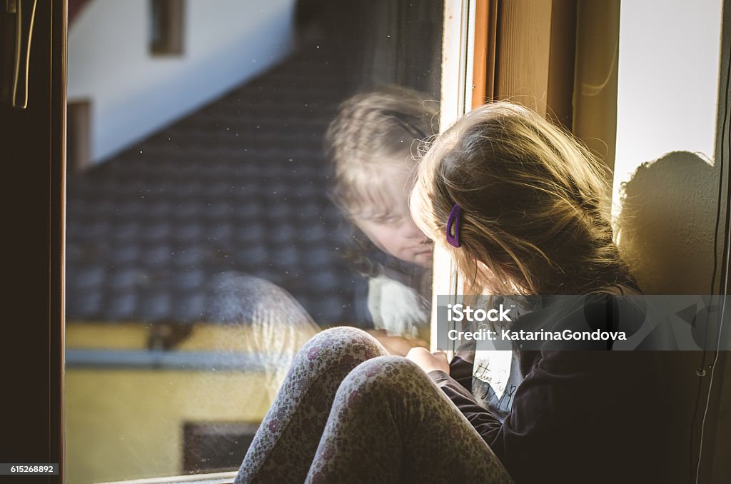 child at the window lovely girl looking through window Blond Hair Stock Photo