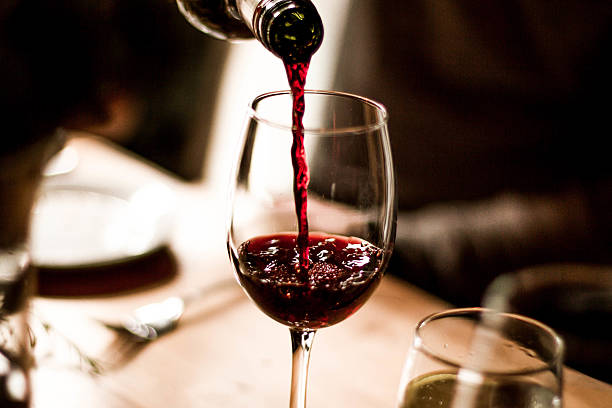 Wine Pouring into Glass Red wine being poured into a stem glass at the table. wine stock pictures, royalty-free photos & images