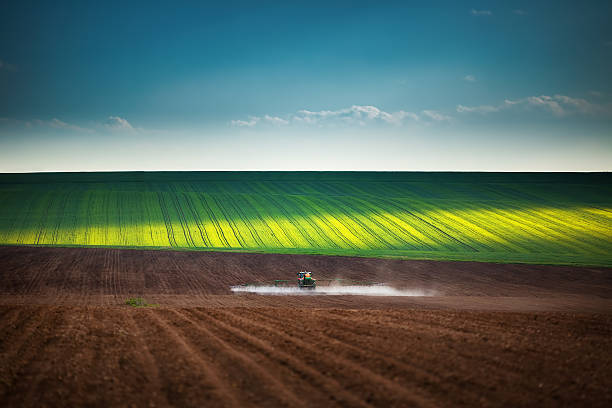 сельское хозяйство трактор вспашка и распылять на поле - высаживать средство передвижения стоковые фото и изображения