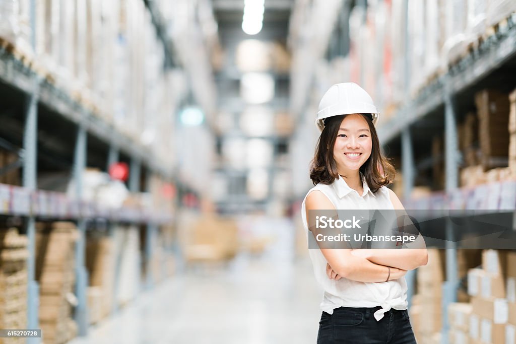 Giovane ingegnere o tecnico asiatico sorridente, magazzino sfocato sfondo - Foto stock royalty-free di Fabbrica