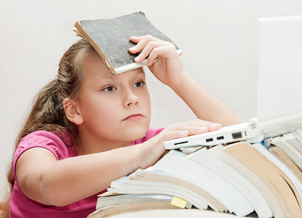 istock Girl child with a book looking laptop. 615271808
