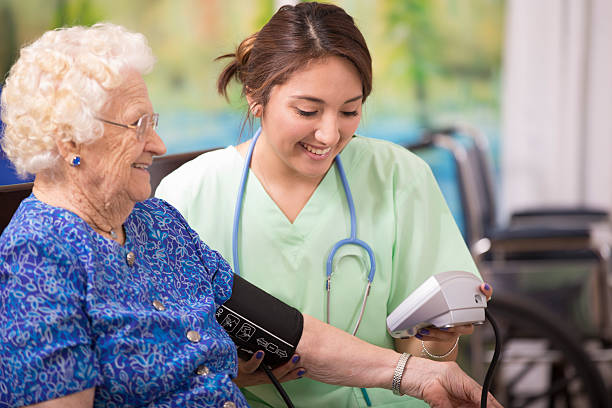 Home healthcare nurse checks blood pressure of elderly woman. Latin descent female nurse or doctor checks blood pressure of a senior woman patient.  Home or clinic setting.  Woman is over 100 years old! over 100 photos stock pictures, royalty-free photos & images