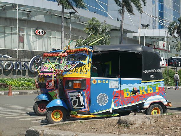Jakarta, Indonesia - September 29, 2016: View of Jakartaâs three wheeled taxis on the road in Jakarta. Cars are on the road. People are around the area.