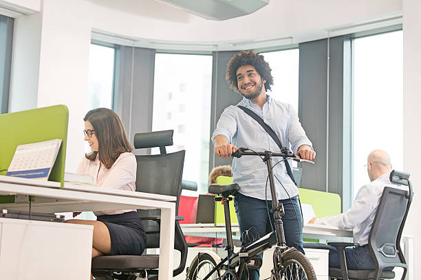 istock Young businessman walking with bicycle while colleagues working in office 615275950