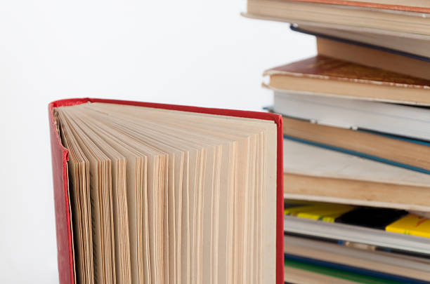istock Stack of hardback books and old open book on white 615275994