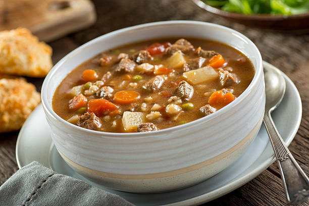 Beef and Barley Soup A bowl of delicious beef and barley soup with carrots, tomato, potato, celery, and peas. soup stock pictures, royalty-free photos & images