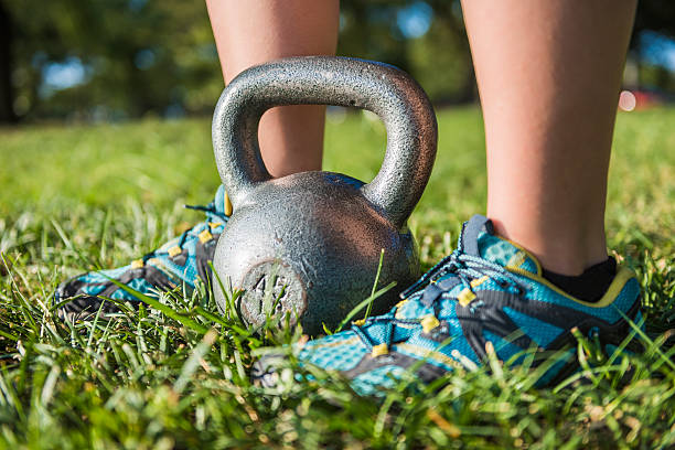istock Woman's legs with sneakers in grass with 45 pound kettlebell 615278854