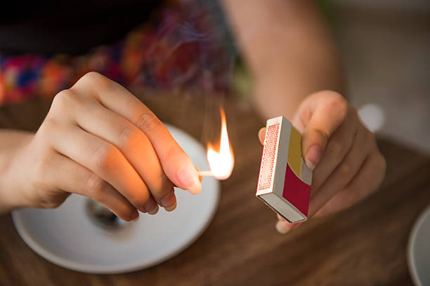 istock Closeup of female hands lighting a match on box 615279926