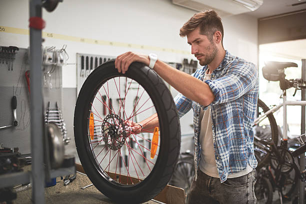 istock Mechanic repairing bicycle wheel 615280954
