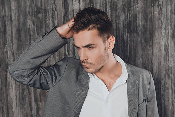 istock Attractive man in suit on the grey background touching hair 615280958