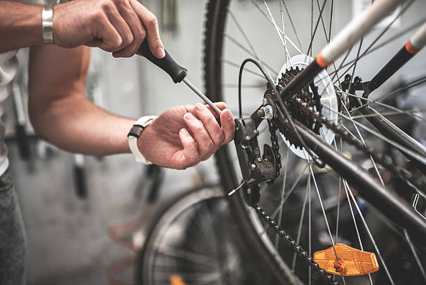 Mechanic repairing bicycle rear wheel Close up shot on male hands inside bicycle store while repairing the gearshift on rear wheel of a mountain bike. mountain bike photos stock pictures, royalty-free photos & images