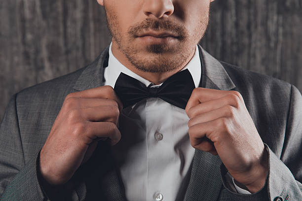 istock young man fastening a bow-tie on his shirt 615282246