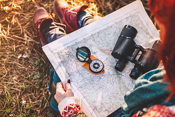 Compass on background of map in the forest Traveler young woman searching direction with a compass on background of map in the forest orienteering stock pictures, royalty-free photos & images