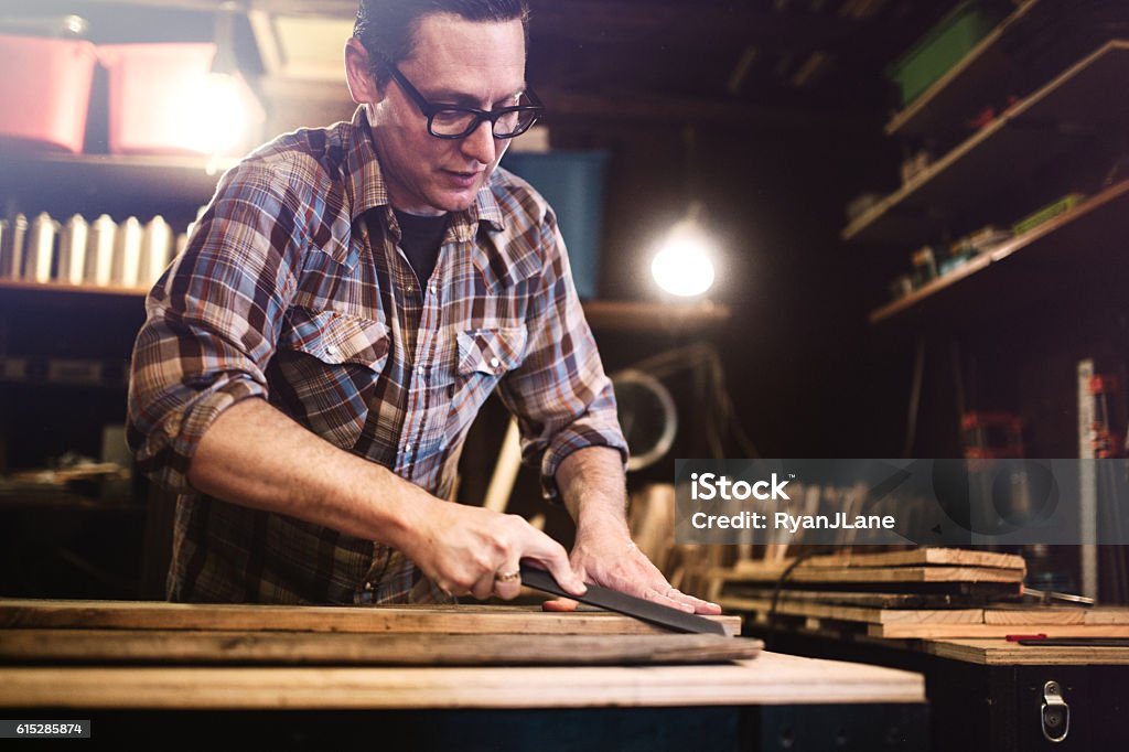 Artist Working With Wood in Studio A craftsman works in his small shop studio space to create beautiful hand crafted art from reclaimed materials to sell at local markets or his online store.  Horizontal image. Wood - Material Stock Photo