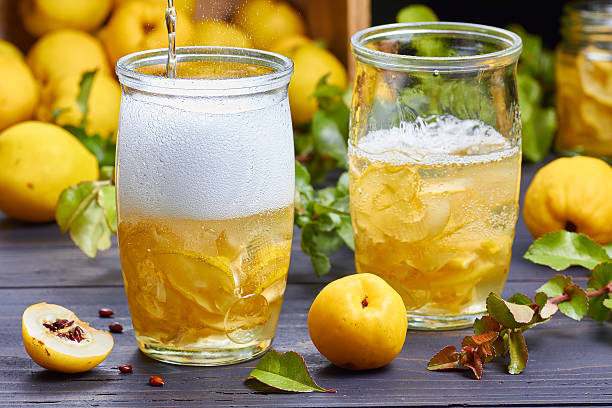 carbonated drink with syrup of japanese quince on fresh fruits carbonated drink with syrup of japanese quince on fresh quince fruits background over dark wooden table cydonia stock pictures, royalty-free photos & images