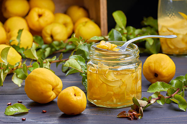Syrup of japanese quince on fresh fruits background Syrup of japanese quince on fresh fruits background over dark wooden table. cydonia stock pictures, royalty-free photos & images