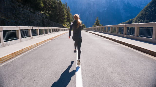 Young woman running in the middle of a road