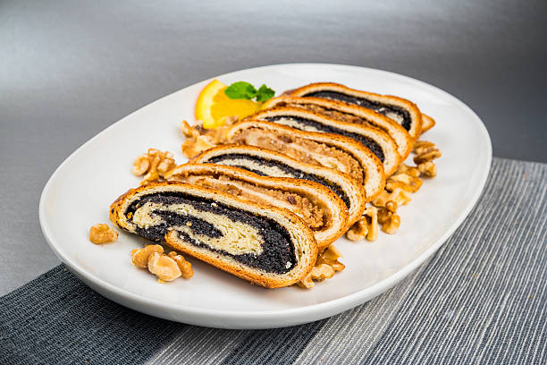Studio photo of  Poppy Seed and Walnut Roll Slices on white serving plate against gray background.