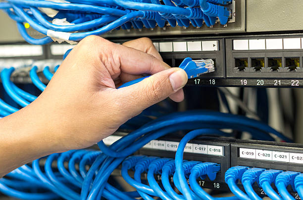 istock hand holding and pluging network cable connect to router 615388212