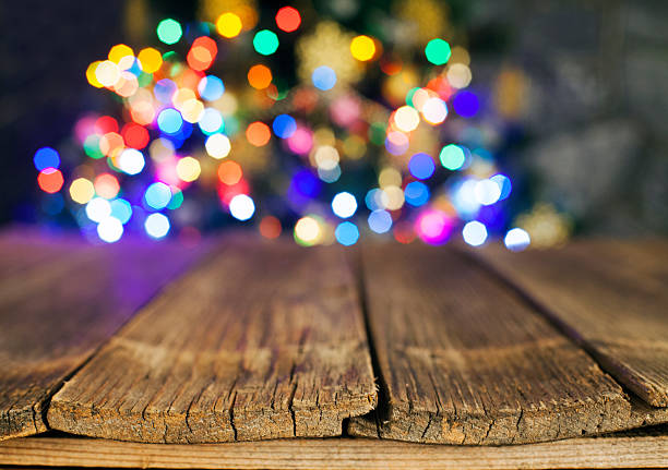 istock Christmas tree, holiday lights behind wooden table. Copyspace. 615390396