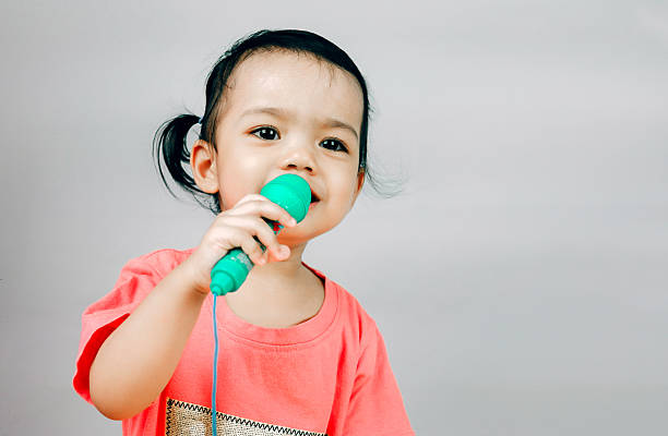 istock Young girl holding a microphone isolated on the white background 615390844