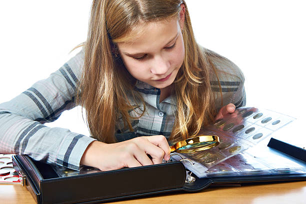 istock Girl inspecting her collection coins isolated 615391892