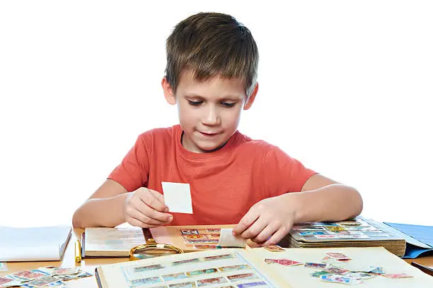 Boy with his collection of old postage stamps isolated white