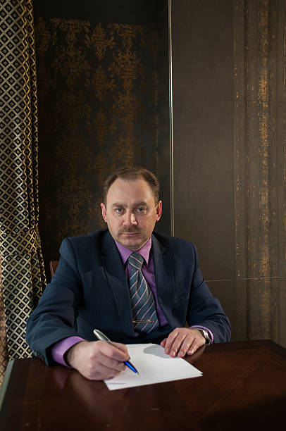 istock Portrait  man at a table with  sheet paper and  pen 615393402