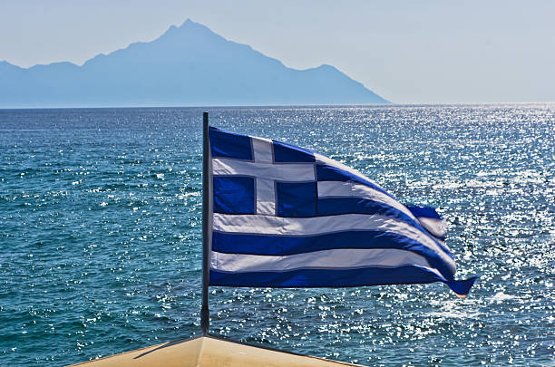 istock Greek flag on sailing ship with mountain Athos in background 615393568
