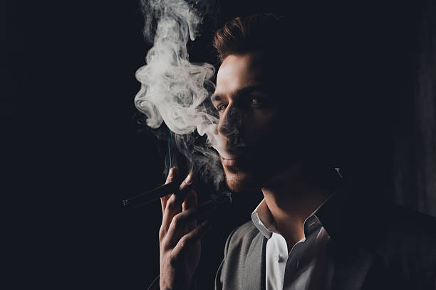 istock Handome man in suit  smoking a cigar 615398348