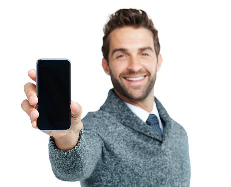 Studio portrait of a handsome businessman showing a phone with a blank screen against a white background