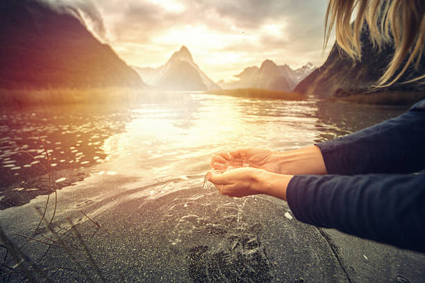 Human hand cupped to catch fresh water from lake, NZ Human hand cupped to catch the fresh water from the lake, Mitre peak reflection on lake surface. mitre peak stock pictures, royalty-free photos & images