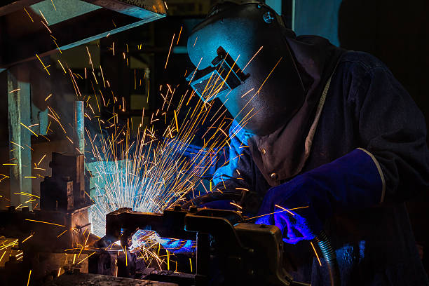 istock worker welding metal with sparks at factory 615403798
