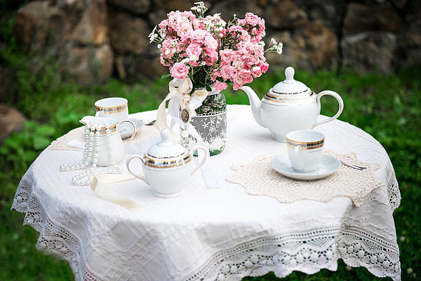 istock table with white lace tablecloth,pink flowers in jar 615411136