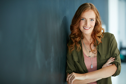 Portrait of a confident young woman leaning against a blackboard